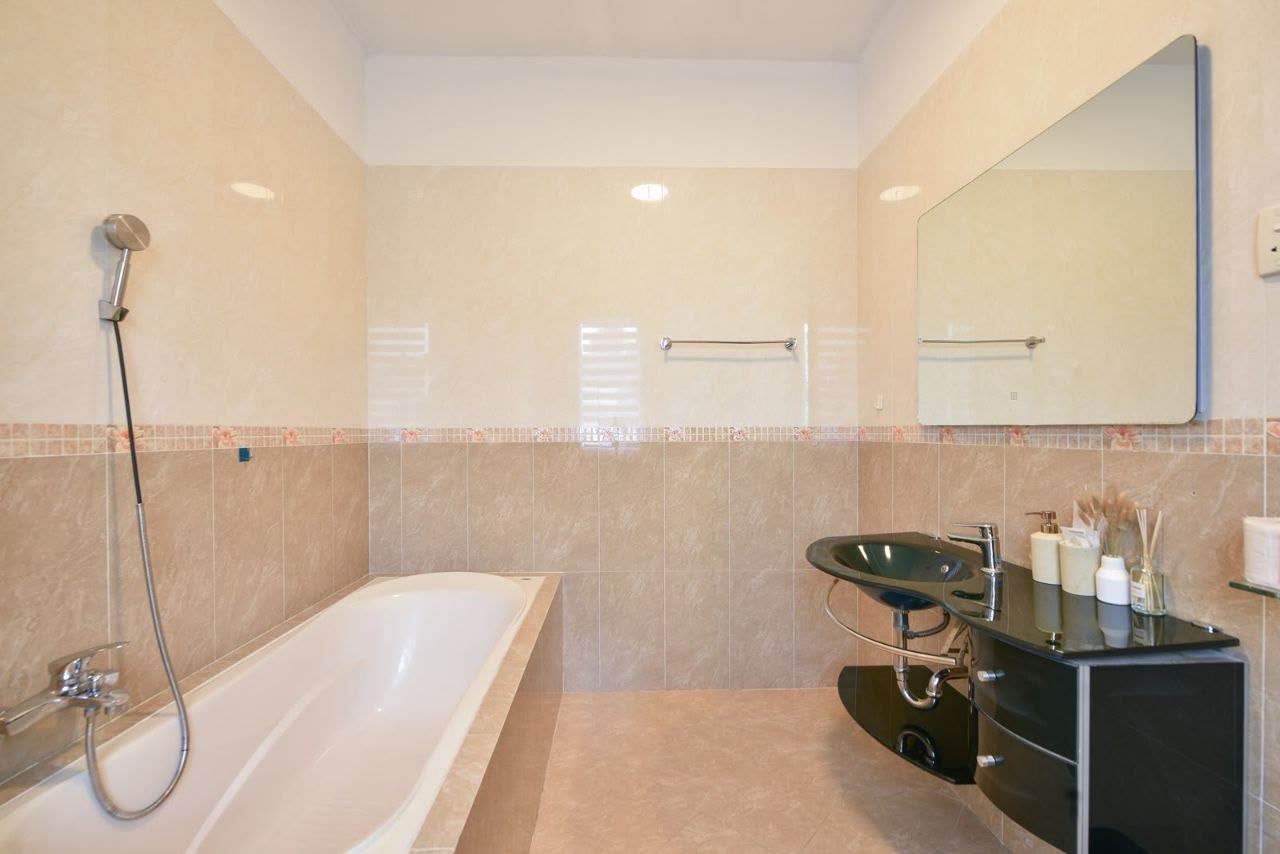 Bathroom with a long bathtub and a hand shower